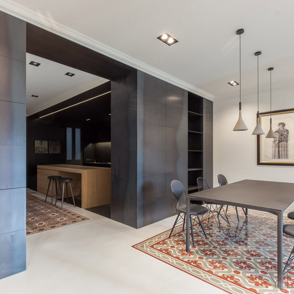 Modern dining area featuring a sleek black table and chairs, with wooden accents and stylish pendant lighting. A patterned rug adds texture, complemented by a framed artwork on the wall. Ideal for contemporary interior design.