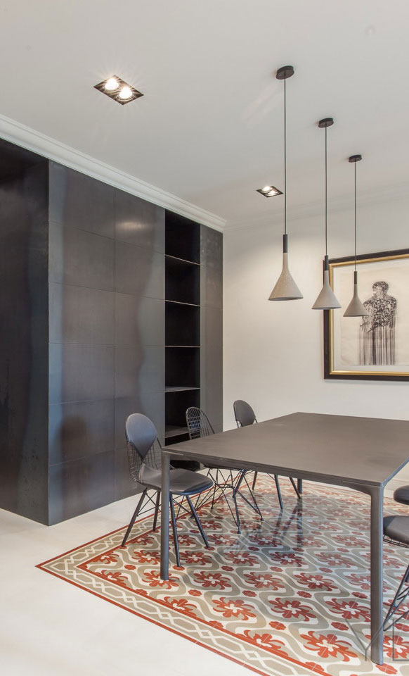 Modern dining area featuring a sleek black table, stylish chairs, and artistic pendant lights, complemented by a decorative patterned rug and a framed artwork on the wall.