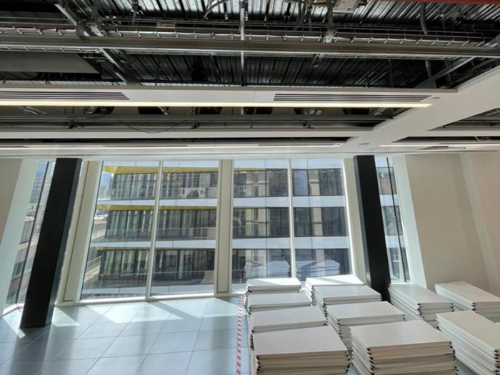 Modern office interior with large windows, stacks of whiteboards, and exposed ceiling elements.