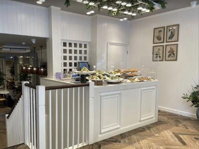 bright, modern café interior with a white counter displaying a variety of delicious food options and decorative plants in the background