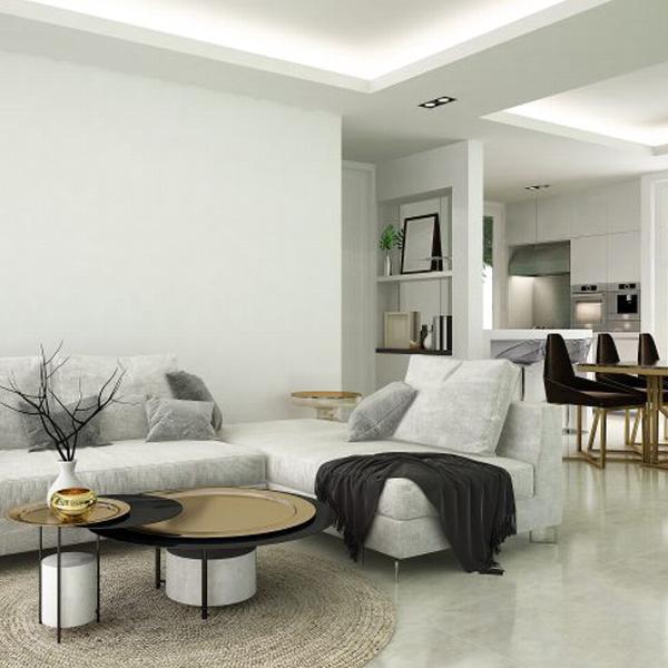 Modern living room with a gray sectional sofa, round coffee table, decorative branches, and stylish dining area in a minimalist design.